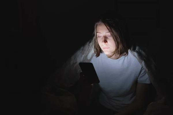 Femme au lit utilise le téléphone tard dans la nuit . — Photo