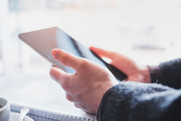 Las manos humanas sostienen una tableta o libro electrónico en un lugar público, vista de cerca . — Foto de Stock