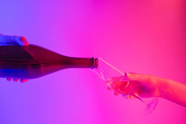 Párty, koncepce oslav: nalévání vína do sklenice na jasném neonovém pozadí — Stock fotografie