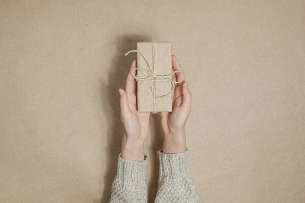 Человеческие руки раздают подарок в коричневой бумаге на соответствующем фоне
. 