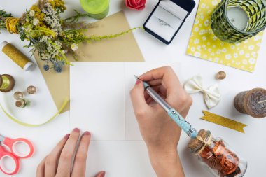 Beyaz defter arkaplanında bir kalem tutan kadın eller