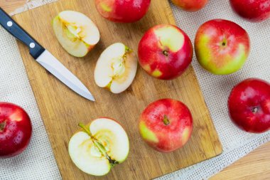 Kırsal ahşap masada olgun sulu elmaların üst görüntüsü. Ev yapımı organik elma ve bıçak, yukarıdan atılmış.