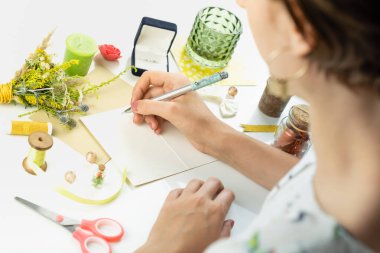 Beyaz defter arkaplanında bir kalem tutan kadın eller