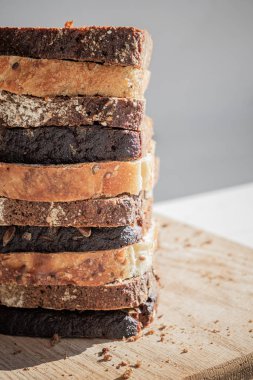 Kesme tahtasındaki bir yığın ekmek dilimi. Doğal ışıkta tahıllı ekmeğin çeşitli türleri.