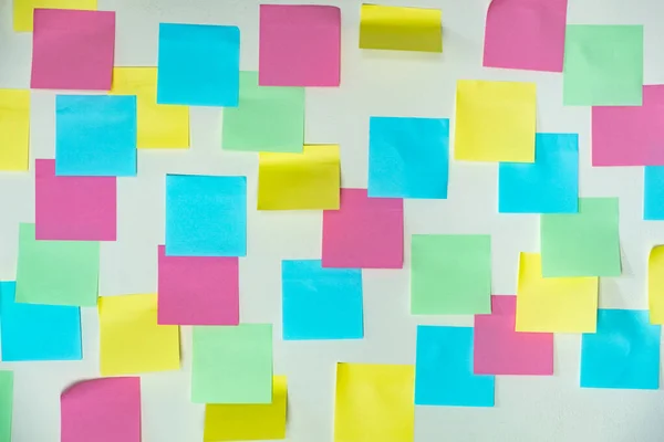 Sticky paper notes on a planning board. Planning, brainstorm, diversity or fresh ideas concept - pattern of empty multicolored paper notes