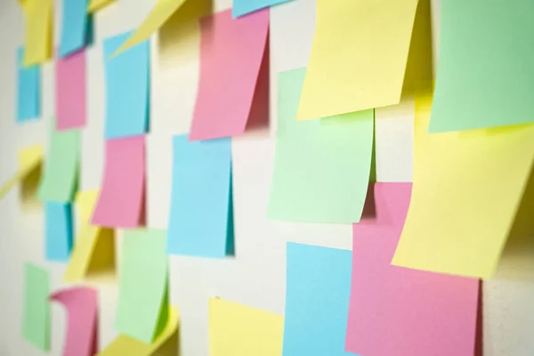 Sticky paper notes on a planning board. Planning, brainstorm, diversity or fresh ideas concept - pattern of empty multicolored paper notes