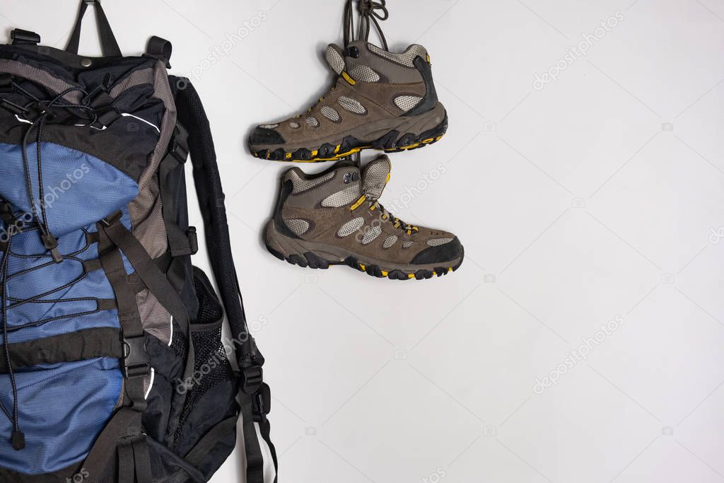Trekking boots and a tourist backpack on white background. Preparing for a hiking trip concept.