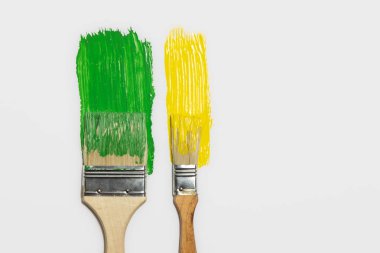 Boya fırçaları ve izole edilmiş yeşil ve sarı boya izleri. Resim, yenileme, ev ve ev işleri kavramı