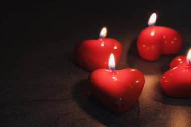 Kalp şeklinde mumlar karanlıkta yanıyor. Sevgililer Günü kavramı.