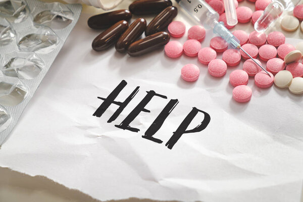Word help in the pile of pills, tablets and syringes. Concept of substance abuse, drug overdose or illegal drugs dependancy