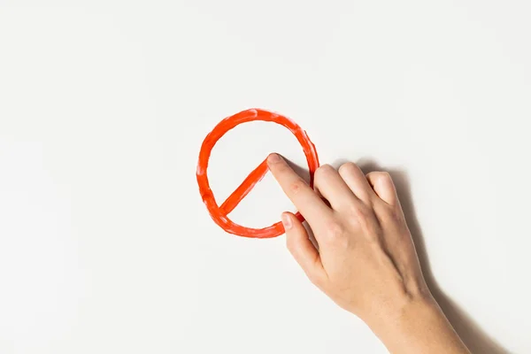 Δάχτυλο σχεδιάζει μια πινακίδα απαγόρευσης με κόκκινη μπογιά σε λευκό φόντο — Φωτογραφία Αρχείου