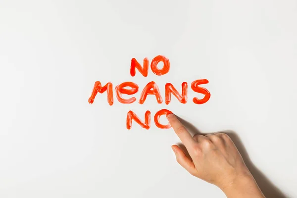 Doigt des femmes dessine une phrase "Non signifie non" avec de la peinture rouge sur un fond blanc . — Photo