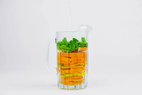 Grande vaso di vetro con agrumi e menta su sfondo bianco . — Foto Stock