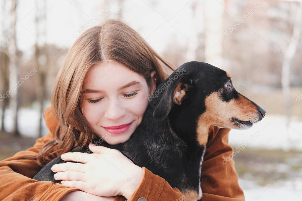 Human being happy with a dog. Loving pets concept: happy young woman hugs her dachshund at a walk