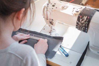 Terzi kadın kumaş parçası, omuz manzaralı. Dikiş makinesinde dikiş diken kadın profesyonel iş yapıyor, iş gücü kavramı