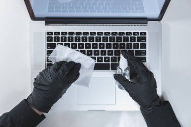 Laptopun klavyesini dezenfektanla temizliyorum. Hijyen ve virüs kavramı iş yerinde veya evde yayılmayı önler