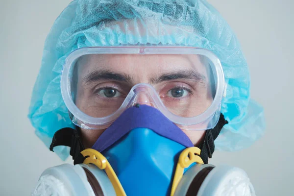 Man in protective face mask, eyeglasses and head protection, focus on eyes. Medical personell, scientist or MD in work gear, concept of covid-19, virus, epidemic and vaccine development