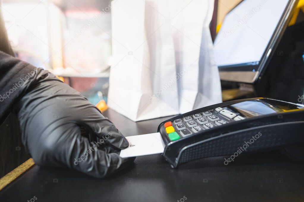 Using credit card for payment, close-up view. Human hand holds a debit payment card to a POS terminal at a shop cashier desk