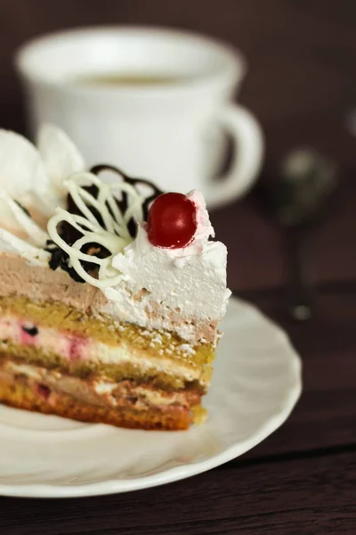 Pastel con crema y cereza sobre un fondo oscuro — Foto de Stock