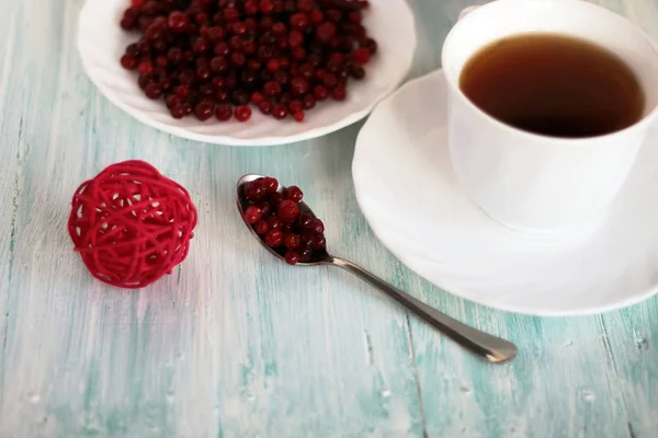 Frozen cranberry, cup of tea on wooden background — Stockfoto