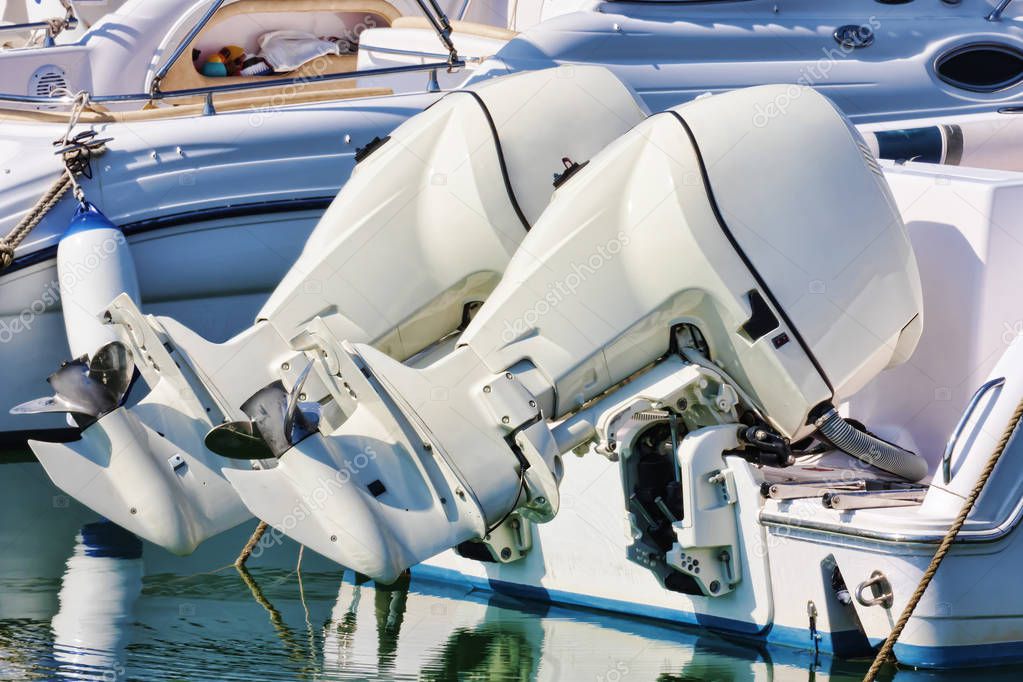 Couple of white outboard engines mounted on white boat