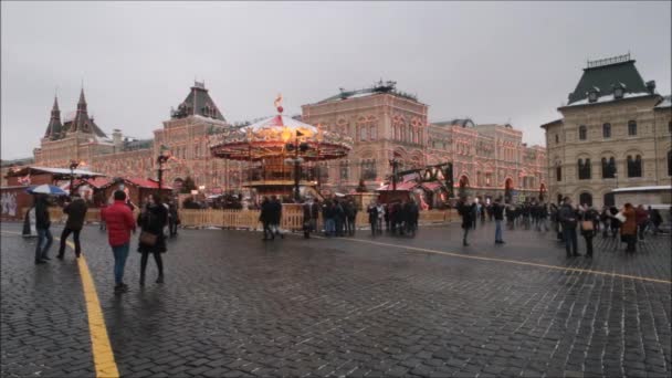 Moszkva, Orosz Föderáció - Január 28, 2017: Kreml Vörös tér: Az emberek élvezik az életet a Vörös téren egy felhős téli napon körhinta és a táj a luxus bevásárlóközpont Gum State Áruház fedett fények — Stock videók