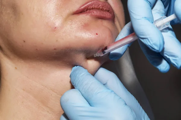 Dermatolog kozmetolojist güzellik kliniğinde orta yaşlı bir hastaya botulinum toksini kozmetik enjeksiyon uyguluyor