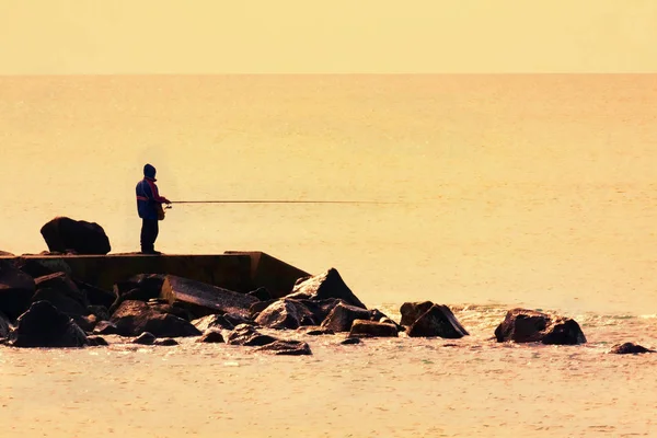 Fisherman at sunset on cliff — Stock Photo, Image