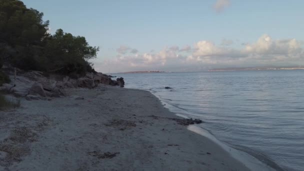 夕阳西下在寂寞的海滩上 平静的海水缓缓地冲破岸边茂密的植被和地平线上松软的白云 — 图库视频影像