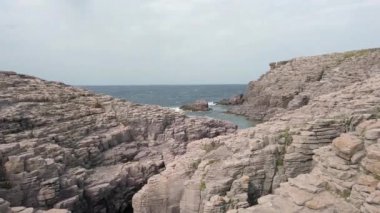 İtalya 'nın Sardunya, Mezza Luna adlı kıyı bölgesindeki Aziz Peter adasında mavi denize bakan büyük uçurumları ve kayaları olan güzel bir doğa.