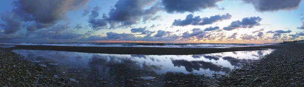 Csodálatos panoráma látványosság naplementekor kavicsos strandon homokkal — Stock Fotó