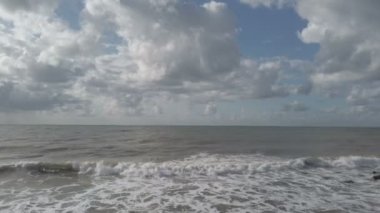 Stormy evening at the beach with rough sea splashing on the shore, a lot of foam water,  and overcast sky with dramatic light