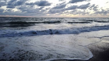 Sahile vuran dalgalar, yayılan günbatımı ışığı 