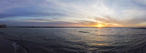 Удивительный панорамный закат с оранжевым и голубым пастельным цветом на римском побережье в районе Остия Лидо, красивые сумерки и отражения вверх по воде и расслабляющее настроение — стоковое фото