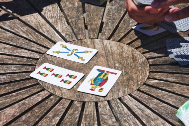 Turin, Italy - May 15, 2014: During coffee break, the employees play Trump in a circular wooden table, people enjoy traditional Neapolitan cards. clipart