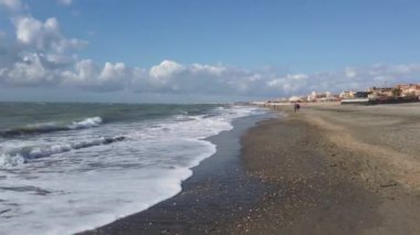 Pov, güzel güneşli bir günde kumsalda geziniyor Ostia Lido 'daki Roma kıyılarında su kenarında yürüyor..