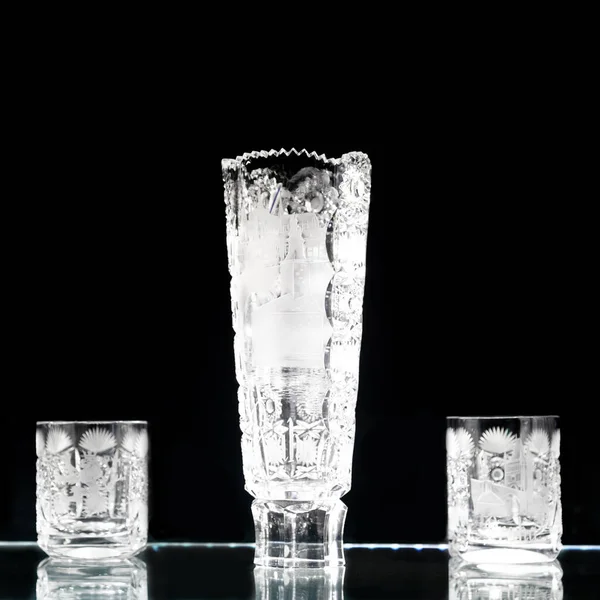 Set of crystal glasses and a vase on a dark background, crystal glassware