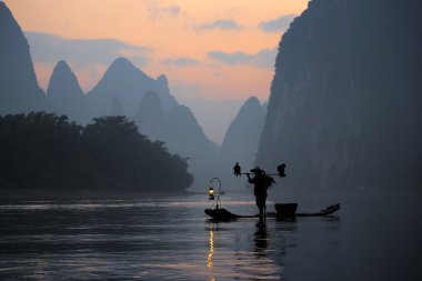 Siluet balıkçı ve Guilin Çin karabatak.