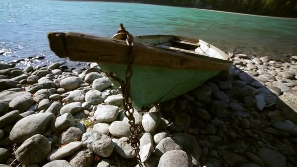 Altes grünes Holzboot steht am Ufer eines Gebirgsflusses — Stockvideo