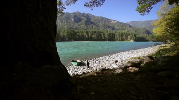 Old wooden green boat is on the shore of a mountain river — Stock Video