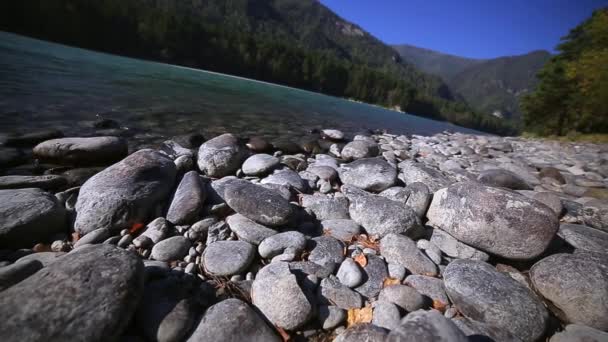 Камни на берегу бирюзовой горной реки — стоковое видео
