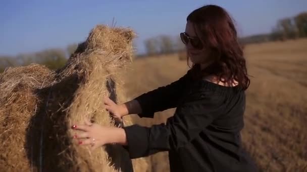 Girl in a black jacket and sunglasses standing near haystack, lifestyle — Stock Video