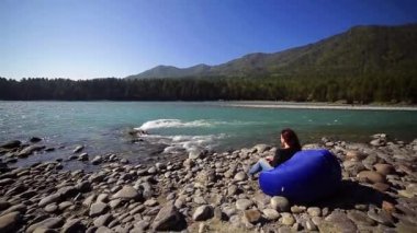 Altay, Katun turkuaz dağ Nehri'nin kıyısında bir sandalye çantada kadın rahatlatır