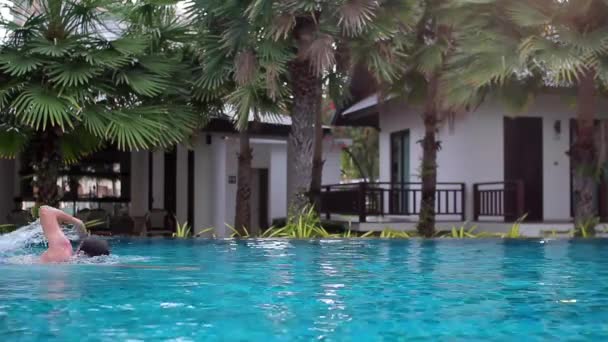 Un jeune homme avec des lunettes pour plonger et nager dans la piscine — Video