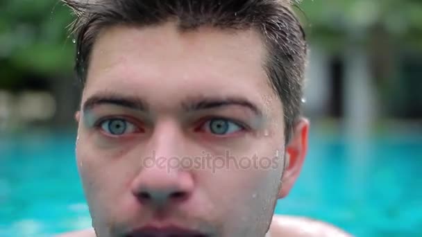 Junger glücklicher Junge mit blauen Augen blickt in die Kamera und taucht in den Pool — Stockvideo