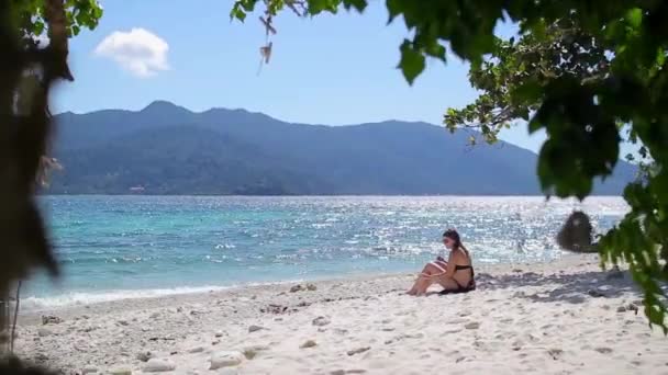 검은 수영복 여자 바다 해변에 앉아서 담배를 피우는. — 비디오