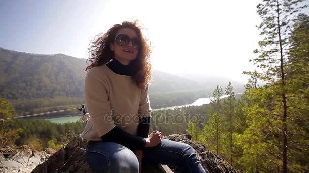 Mujer sentada en el fondo del bosque de otoño y el río de montaña y sonrisas — Vídeos de Stock