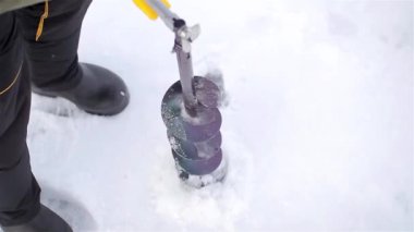 adam kış balıkçılık için delik delik yapar