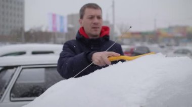 adam bir fırça ile kar arabadan temizler