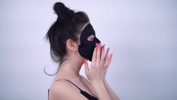 A girl with pinned hair smoothes a fabric mask on her face. Standing in profile — Αρχείο Βίντεο